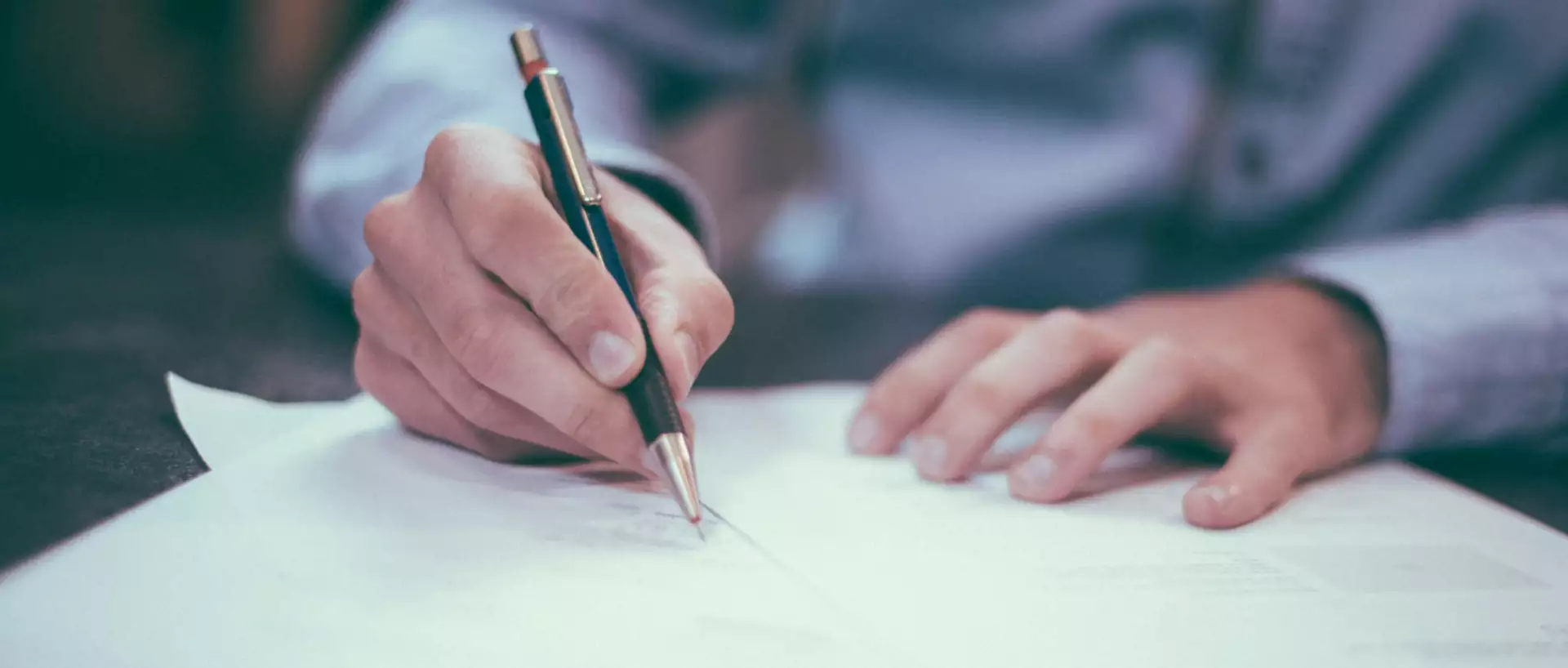 A person writing on a piece of paper with a pen